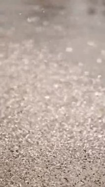 Çeşme. Su püskürtme. Yağmur. Yakın plan. Su yüzeye yayılır, asfalta, güneş ışığında parlar. Su sıçratıyor. Damlalar. Yaz güneşli bir gün.