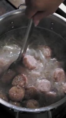 Köfte kaynatın. Yemek pişirmek. Yakın plan. Üst Manzara. Köfteler büyük bir tencerede kaynatılır. Aşçı çorbayı karıştırıyor. Açık büfe restoran mutfağı.