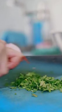 Yemek pişirmek. Şef sebze keser. Açık büfe restoran mutfağı. Yakın plan. Şef taze maydanozu küçük parçalara ayırıyor. Plastik tahta üzerinde keskin, büyük bir mutfak bıçağıyla..