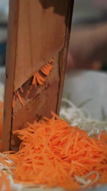 Yemek pişirmek. Bir rende dilimle. Açık büfe restoran mutfağı. Yakın plan. Şef taze havucu öğütücüye koyup büyük bir kâseye koyuyor.