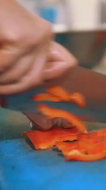 Yemek pişirmek. Şef sebze keser. Açık büfe restoran mutfağı. Yakın plan. Şef, plastik tahta üzerinde keskin, büyük bir mutfak bıçağıyla taze çan biberini küçük parçalara ayırıyor..