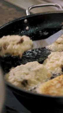 Patates köftesi. Patates kızartması. Yemek pişirmek. Patates keki, zuela. Açık büfe restoran mutfağı. Yakın plan. Aşçı çıtır patates kızartması yapıyor, kızgın yağda kızarıyor..
