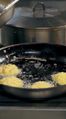 Patates kızartması. Patates köftesi. Yemek pişirmek. Patates keki, zuela. Açık büfe restoran mutfağı. Yakın plan. Aşçı çıtır patates kızartması yapıyor, kızgın yağda kızarıyor..