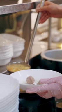 Açık büfe restoranı. Kendi kendine hizmet veren kafeterya. Yakın plan. Garson, koruyucu eldivenler içinde, müşteri için sıcak çorbayı kaseye dolduruyor. Yemek pişirmek. sağlıklı gıda.