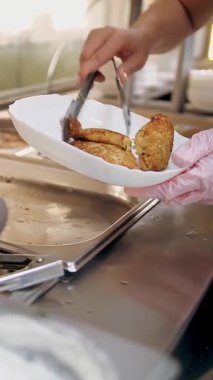 Açık büfe restoranı. Kendi kendine hizmet veren kafeterya. Yakın plan. Garson, koruyucu eldivenlerle, müşteriler için yemek hazırlıyor. Yemek pişirmek. sağlıklı gıda.