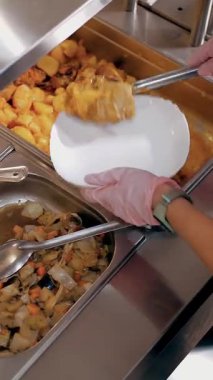 Açık büfe restoranı. Kendi kendine hizmet veren kafeterya. Yakın plan. Garson, koruyucu eldivenlerle, müşteriler için yemek hazırlıyor. Yemek pişirmek. sağlıklı gıda.