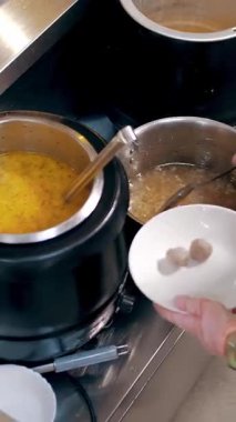 Açık büfe restoranı. Kendi kendine hizmet veren kafeterya. Yakın plan. Garson, koruyucu eldivenlerle müşteriye sıcak çorba dolduruyor. Yemek pişirmek. sağlıklı gıda.