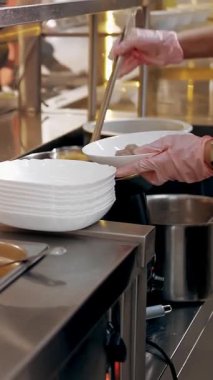 Açık büfe restoranı. Kendi kendine hizmet veren kafeterya. Yakın plan. Garson, koruyucu eldivenlerle müşteriye sıcak çorba dolduruyor. Yemek pişirmek. sağlıklı gıda.