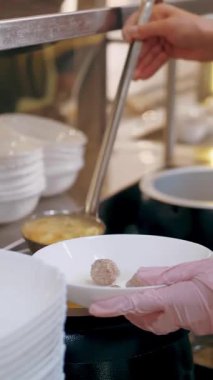Açık büfe restoranı. Kendi kendine hizmet veren kafeterya. Yakın plan. Garson, koruyucu eldivenler içinde, müşteri için sıcak çorbayı kaseye dolduruyor. Yemek pişirmek. sağlıklı gıda.