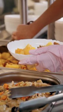 Açık büfe restoranı. Kendi kendine hizmet veren kafeterya. Yakın plan. Garson, koruyucu eldivenler içinde, müşteri için sıcak çorbayı kaseye dolduruyor. Yemek pişirmek. sağlıklı gıda.