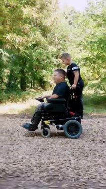 Engelli biri. Baba ve oğul. Babalar Günü. Baba ve küçük tatlı oğlu bir yaz günü parkta yürüyorlar. Babam tekerlekli sandalye kullanıcısı..