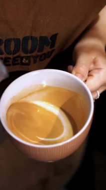 Kahve içeceğim. Sütlü. Yakın plan. Kahveci sütlü latte sanatını küçük beyaz bir fincana çiziyor..