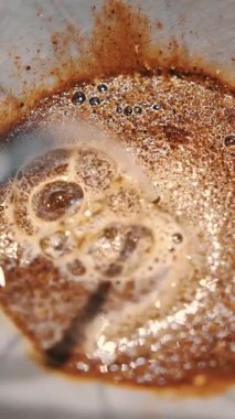 Damlayan kahve demleniyor. Yakın plan. Kahveci taze kahve çekirdeklerinin üzerine özel bir çaydanlıktan kaynar su döker.