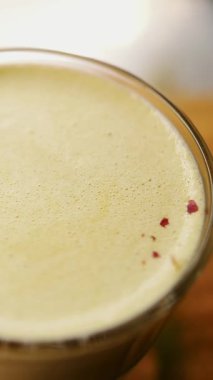 matcha latte. Yakın plan. Üst Manzara. Kahveci kokteyl dekore eder, süt ve kibrit karışımını kuru çiçek yapraklarıyla karıştırır.