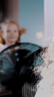 Rüzgarda dalgalanan saçlar. Yakından, sevimli küçük kız eğleniyor. Yelpazenin önünde duruyor, hava dalgalı saçlarını rüzgârda süzüyormuş gibi.