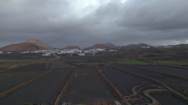 panorama overview drone white houses in black lava field from volcanic ash, Canary Islands Spain, cloudy day 2023. High Quality 4k Cinematic footage.