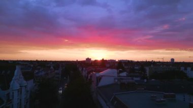 Pembe turuncu güneş şehri, Berlin Steglitz şehir merkezi üzerinde bulutlu bir gün batımı, Almanya 'nın başkenti, 2023 yaz akşamı panorama 4K hava aracı..