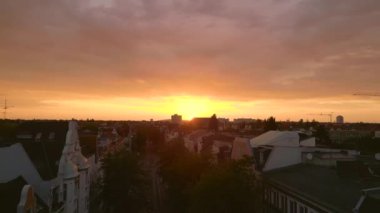 Pembe turuncu güneş şehri bulutlu gün batımı Berlin Steglitz şehir merkezinde, Almanya 'nın başkenti, 2023 yaz akşamı uçuş üstü İHA 4K hava aracı..