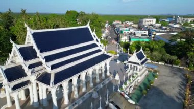 Arkasında tropikal manzarası olan sakin bir Tayland tapınağının üzerinden geçen insansız hava aracı.