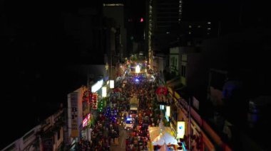 Kentsel ortamda panorama drone Bustling gece pazarı. Kalabalık, canlı bir gece pazarında renkli ışıklarla alışveriş yapıyor.