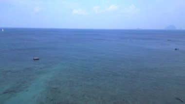 Yeşillik yemyeşil tropik plajlar. Geri geri uçun. Palmiye ağaçları ve kristal berrak sularla kaplı sakin bir tropikal plajın insansız hava aracı görüntüsü.