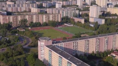 Kentsel spor kompleksi ve yerleşim alanı. Drone görüntülerini daire içine al. Kalabalık bir şehrin yüksek binalarının ortasındaki bir spor sahasının kuş bakışı görüntüsü.