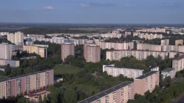 Berlin 'de apartman blokları olan bir manzara. Modern yüksek binalar ve ağaçlarla dolu bir yerleşim bölgesinin sağdaki drone görüntüsüne döndür