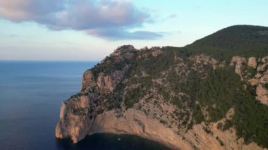 Deniz kenarındaki uçurum, gün batımının sıcacık parıltısıyla güneşleniyor. İnsansız hava aracını çek. Yüksek kalite 4k görüntü