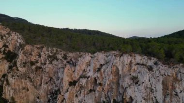 Deniz kenarındaki uçurum, gün batımının ılık parıltısıyla yükselen drone 'un tadını çıkarıyor. Yüksek kalite 4k görüntü