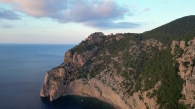 Günbatımının ılık parıltısıyla güneşlenen deniz kenarındaki uçurum geniş yörüngedeki insansız hava aracı. Yüksek kalite 4k görüntü