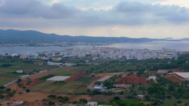 Kırsal alan, kıyı kenti ve tarım arazisi. Panorama yörünge dronu. Sahildeki kentsel-kırsal geçişi gösteren yüksek manzara görüntüsü