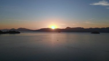 Panorama insansız hava aracı Tranquil gündoğumu Langkawi adalarının etrafındaki sakin deniz üzerinde ufku kırıyor.