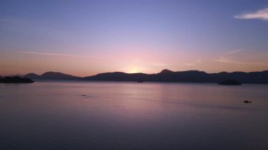 İHA 'nın tepesi aşağıda. Huzurlu güneş doğuyor. Langkawi adalarının etrafındaki sakin denizin üzerinde ufku kırıyor.