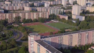 Kentsel spor kompleksi ve yerleşim alanı. Yukarıdan insansız hava aracı görüntüleri. Kalabalık bir şehrin yüksek binalarının ortasındaki bir spor sahasının kuş bakışı görüntüsü.