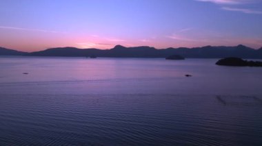 İniş yapan insansız hava aracı Tranquil ve sakin langkawi şafağı okyanus, uzak adalar ve tekneler üzerindeki çarpıcı mor renkleri ile huzurlu ve sakin bir deniz manzarası yaratıyor.