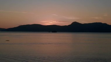 Yükselen insansız hava aracı Tranquil ve huzurlu langkawi şafağı okyanus, uzak adalar ve tekneler üzerinde çarpıcı mor renkler oluşturarak huzurlu ve sakinleştirici bir deniz manzarası yaratıyor.