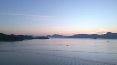 Sağa dön Tranquil ve sakin langkawi şafak okyanus, uzak adalar ve tekneler üzerinde çarpıcı mor renkler, huzurlu ve sakin bir deniz manzarası yaratıyor.