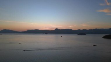 Tranquil ve dingin langkawi seher vaktinin ardından okyanus, uzak adalar ve tekneler üzerinde çarpıcı mor renkler ile sakin ve sakin bir deniz manzarası yaratıyor.