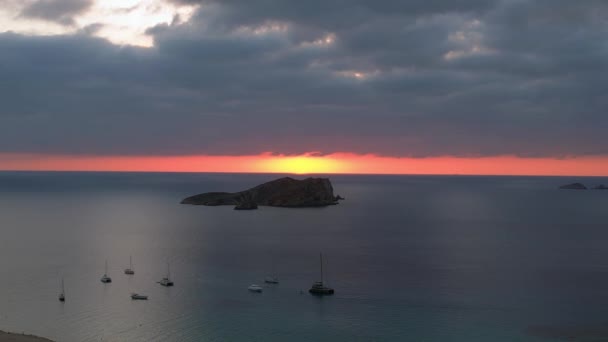イビサのボートと素晴らしい日没の空を伴うビーチの空中ビュー パノラマ軌道ドローン — ストック動画