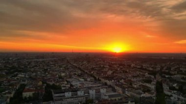 Üstten kumandalı insansız hava aracı. Gündoğumunda uyanan şehir, canlı turuncu gökyüzü olarak sakin şehir manzarası. Sabahın erken saatlerinde çevre ışığı