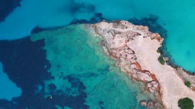 Ibiza 'da tekneli Cala Comte plajı ve çarpıcı bir günbatımı manzarası. dikey kuş bakışı dron 