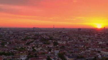 İHA yükseliyor. dingin ve sakin şehir manzarasının panoramik görüntüsü canlı turuncu gökyüzü sıcak gökdelenleri ve çatıları yıkıyor.. 