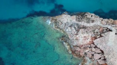 Ibiza 'da tekneli Cala Comte plajı ve çarpıcı bir günbatımı manzarası. dikey kuş bakışı dron 