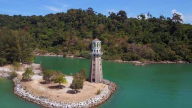 İHA 'yı getirin. Manzaralı tropik bir plajı ve dağ zeminli bir burnun üzerindeki ıssız deniz feneri.