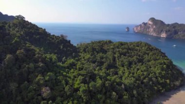 İHA iniyor. Tayland 'da yemyeşil bitki örtüsü olan tropikal adayı çevreleyen turkuaz su. Turkuaz su, yemyeşil bitki örtüsüyle tropikal bir adayı çevreledi.