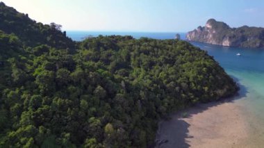 İHA iniyor. Tayland 'da yemyeşil bitki örtüsü olan tropikal adayı çevreleyen turkuaz su. Turkuaz su, yemyeşil bitki örtüsüyle tropikal bir adayı çevreledi.