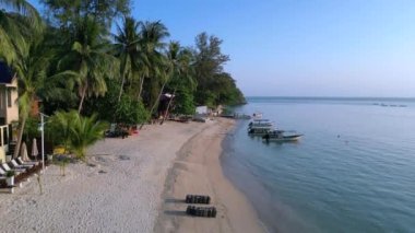 Nazik dalgalara, altın ışığa ve tropik bir sahilde sallanan palmiye ağaçlarına uyanmak. Turkuaz sularda tekneleri olan huzurlu bir cennet ve lüks bir tatil yeri. İHA yükseliyor 