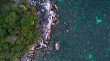 Tropikal bir adanın, turkuaz suların ve kayalık kıyı şeridinin güzelliğini yakalayan bu hava manzarası engebeli kayalıklara ve kıyılara karşı canlı mavi ve yeşil renkler gösteriyor. Yukarıdan aşağıya doğru uçur 