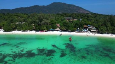 Turistler, turkuaz suya demirlemiş geleneksel Tayland uzun kuyruklu tekneleriyle tropikal bir adada güneşli bir günün tadını çıkarıyorlar. hız rampası Hiperlapse hızlandırılmış zaman aşımı 