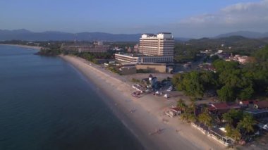 Hız rampası hiperlapse hareket hızı zaman aşımı. Langkawi sahil şeridinin havadan görünüşü, turistlerin berrak mavi suların tadını çıkardığı tropik bir plajdaki otel ve tatil beldelerini gösteriyor.